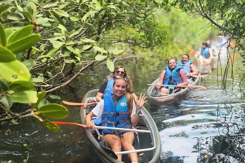 People in canoes on a river surrounded by dense foliage. 1