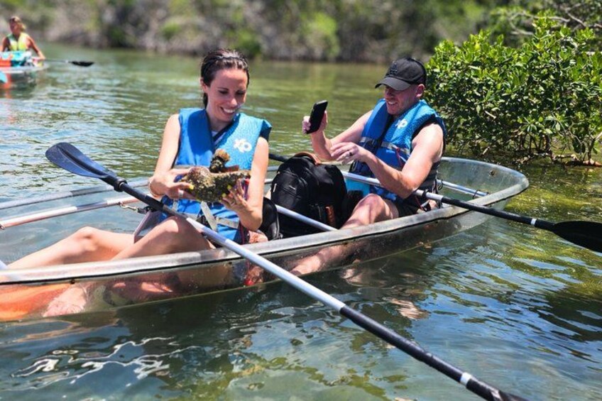 Two people in a canoe on a calm body of water, one holding a smartphone. 3