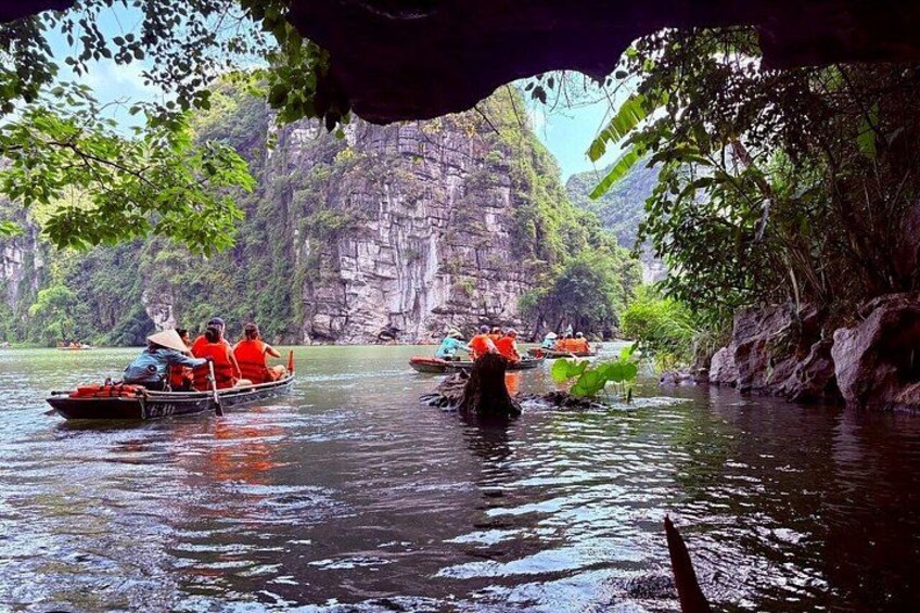 A river with boats, rocky cliffs, and dense foliage. 2