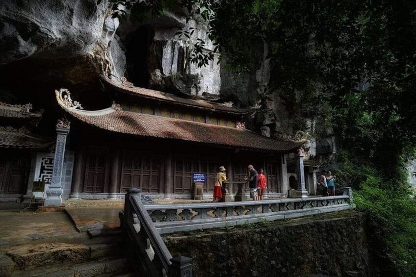 A traditional building with a curved roof, situated on a rocky cliffside with a stone pathway leading up to it. 4
