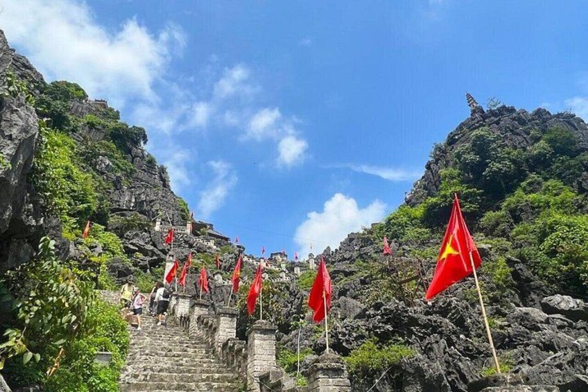 A mountainous landscape with red flags, stone steps, and greenery. 3