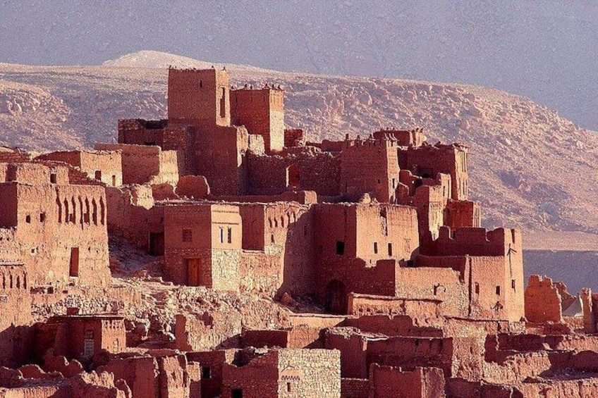 A desert landscape with ancient adobe structures and a mountainous backdrop. 2