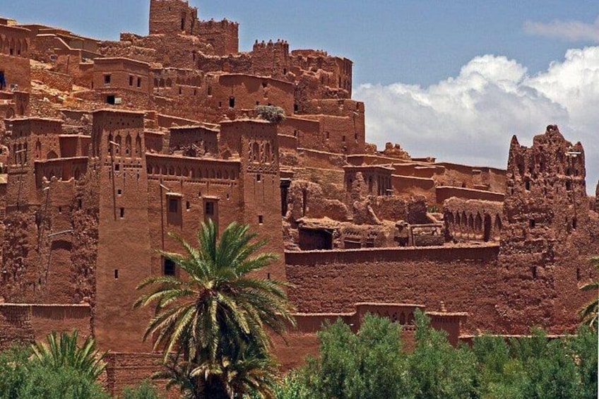 A historic adobe fort with multiple towers and walls, surrounded by greenery. 4