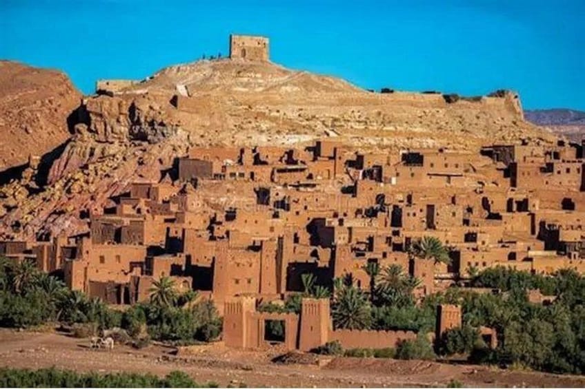 A traditional mud-brick village with a prominent fortress on a hill. 3
