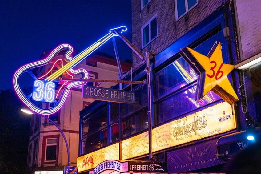 A building with neon signs, including a guitar and the number 36. 2