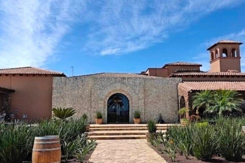 A stone building with a tiled roof, a central archway, and a bell tower. 2