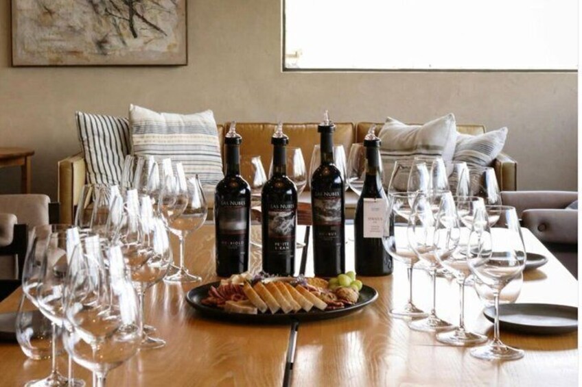 A dining table with wine bottles, glasses, and a plate of food. 3
