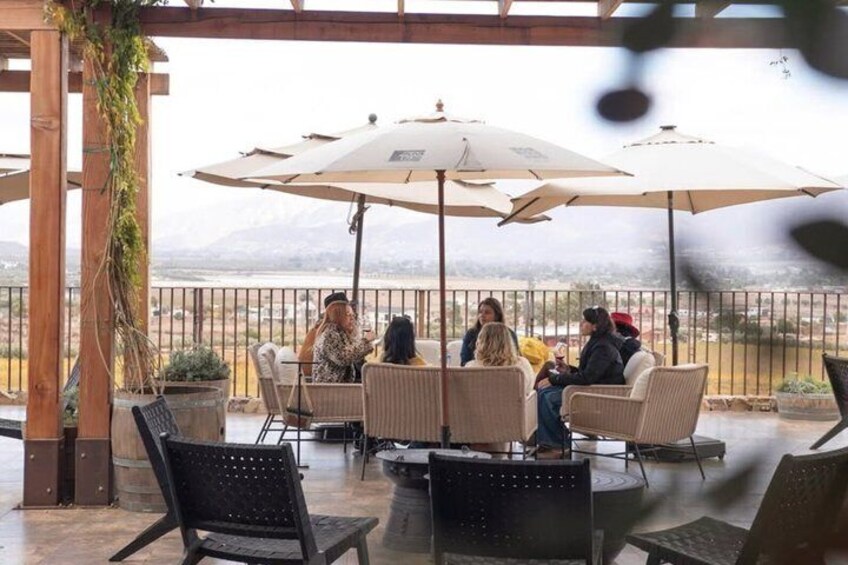 A terrace with outdoor seating, umbrellas, and a view of a mountainous landscape. 1