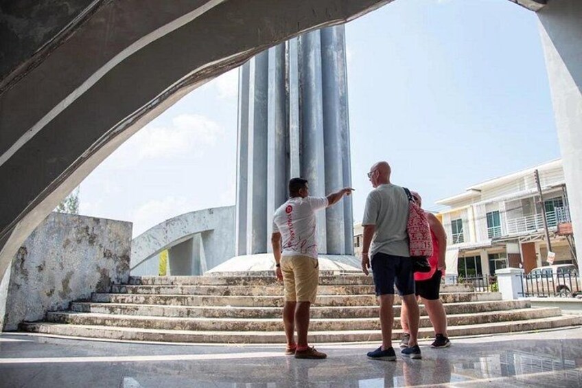 Two people standing on steps under a large structure with a modern design. 2