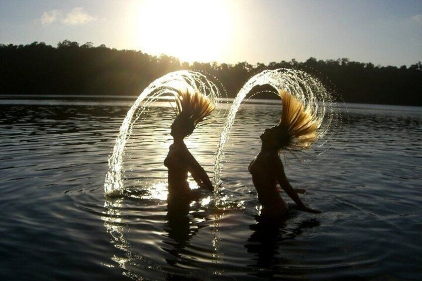 Two people playing with water in a lake at sunset. 5