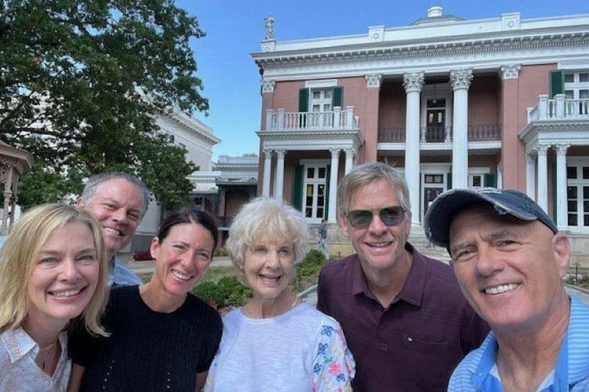A group of people in front of a large, classical building with columns and a portico. 3