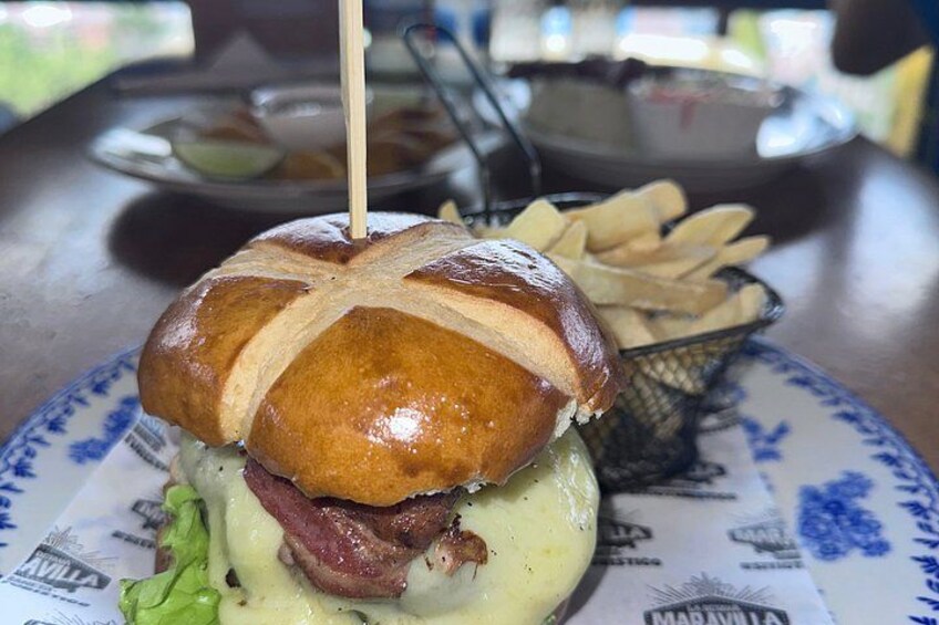 Un sándwich con un palillo, lechuga, queso y tocino, sobre un plato con papas fritas. 3