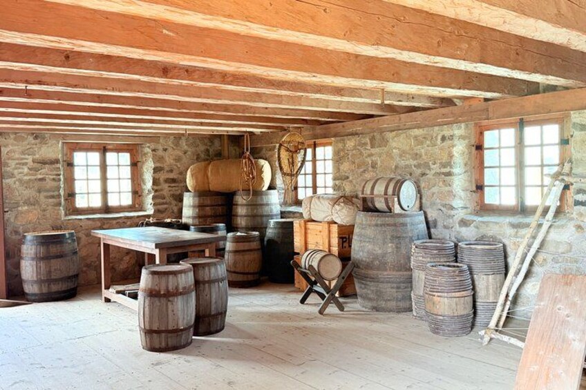 A rustic wooden room with stone walls, wooden barrels, and a ladder. 2