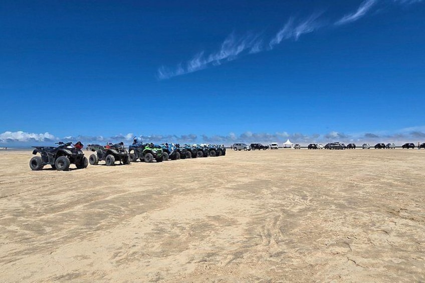A line of ATVs parked on a sandy terrain under a clear blue sky. 5