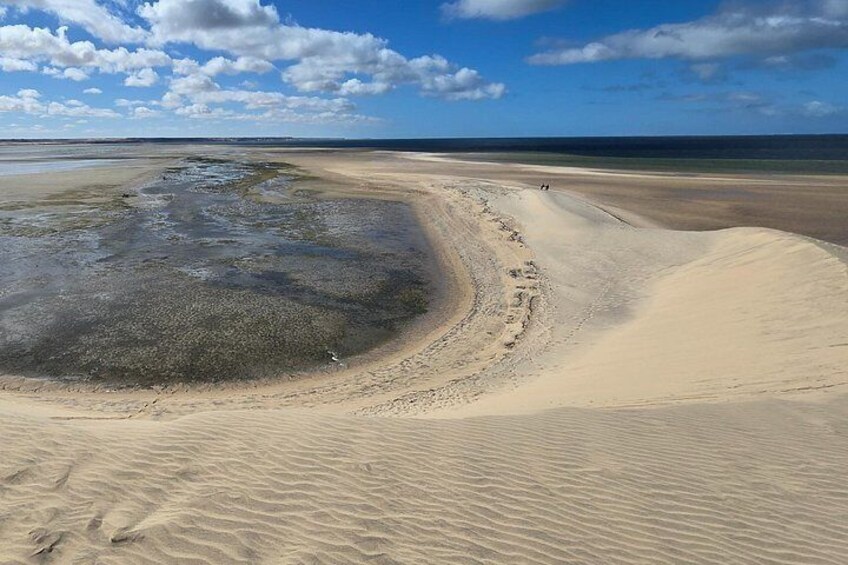 A sandy beach with a curved dune and a small body of water. 4