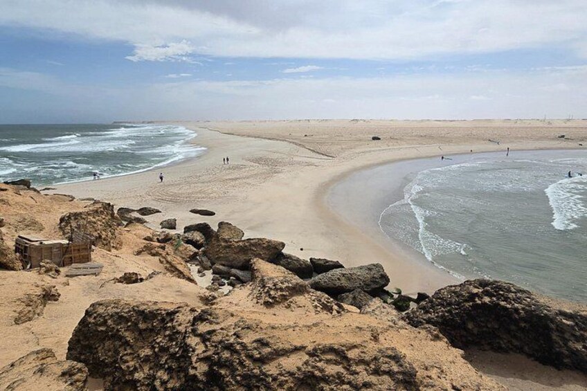 Ein Sandstrand mit Wellen, Felsen und blauem Himmel. 1