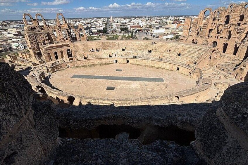 An ancient amphitheater with a circular stage and tiered seating. 3