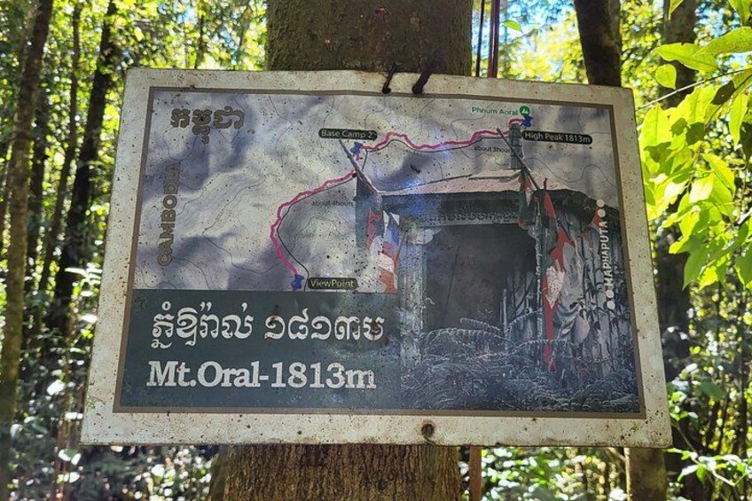 A sign with a map and text in a forested area. 4