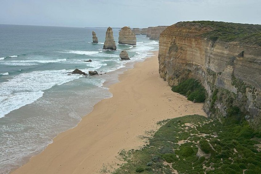 A coastal landscape with a sandy beach, ocean waves, and distinctive rock formations. 1