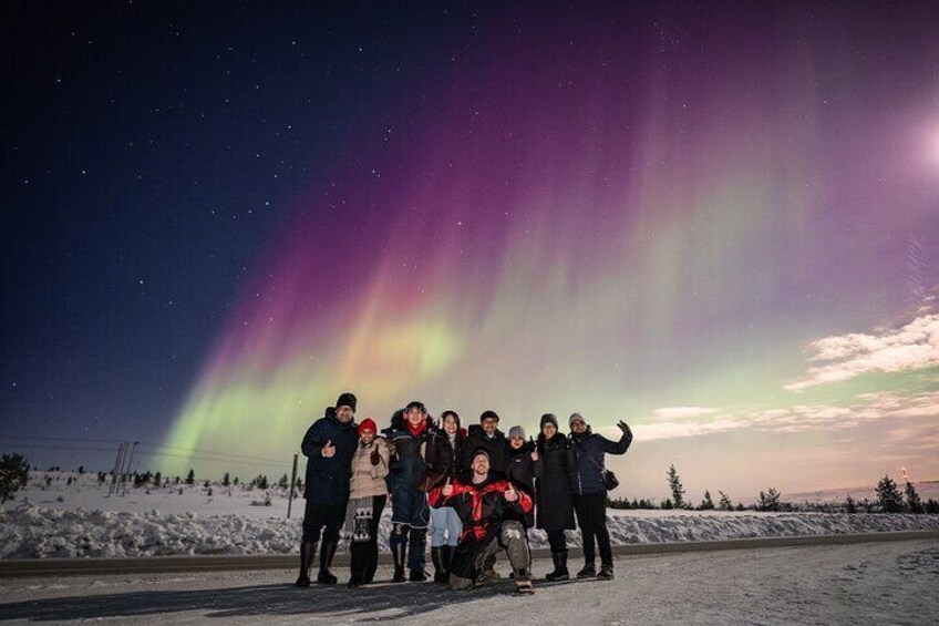 A group of people posing under the aurora borealis. 1
