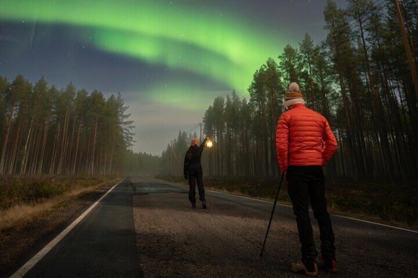 Two people walking on a road with the aurora borealis in the background. 5