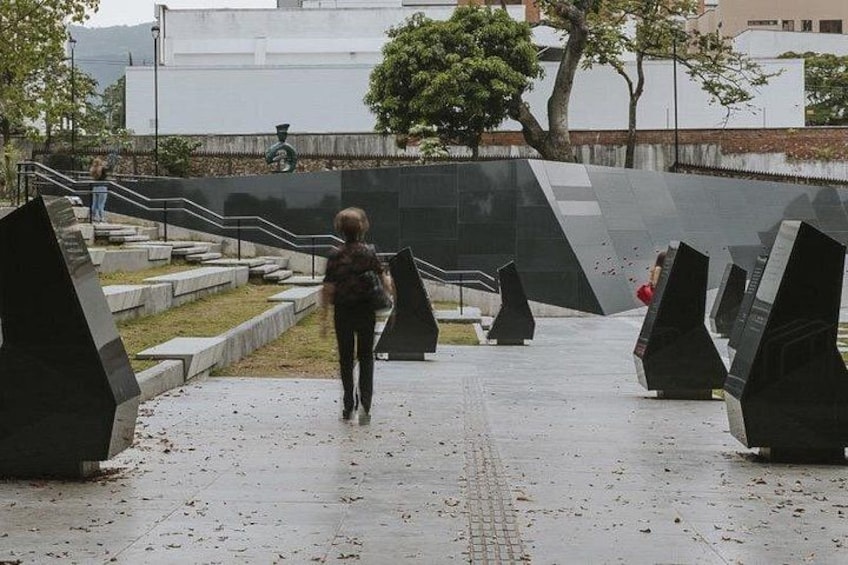 A person walking on a pathway with geometric sculptures and a staircase. 4