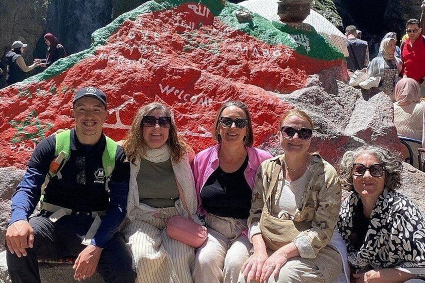 Eine Gruppe von Menschen posiert vor einer großen, bunten Sandskulptur, auf der das Wort 'WELCOME' zu sehen ist. 2