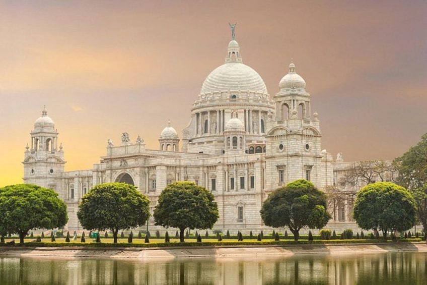 A large white building with domes and towers, surrounded by trees and a body of water. 1