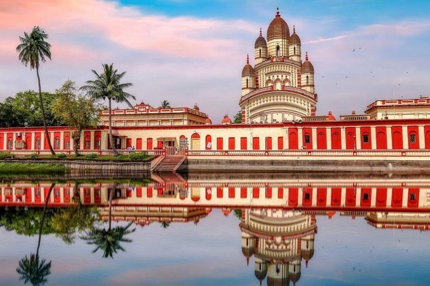 A large, ornate building with multiple domes, a reflection in the water, and palm trees. 2