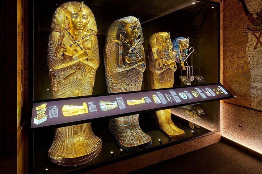 Drie gouden sarcofagen met hiërogliefen, tentoongesteld in een museumvitrine. 1