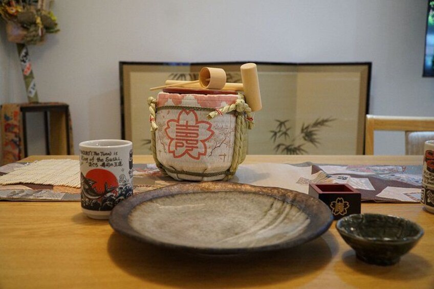 A traditional Japanese tea set on a wooden table with a ceramic plate, a teapot, and a cup. 5