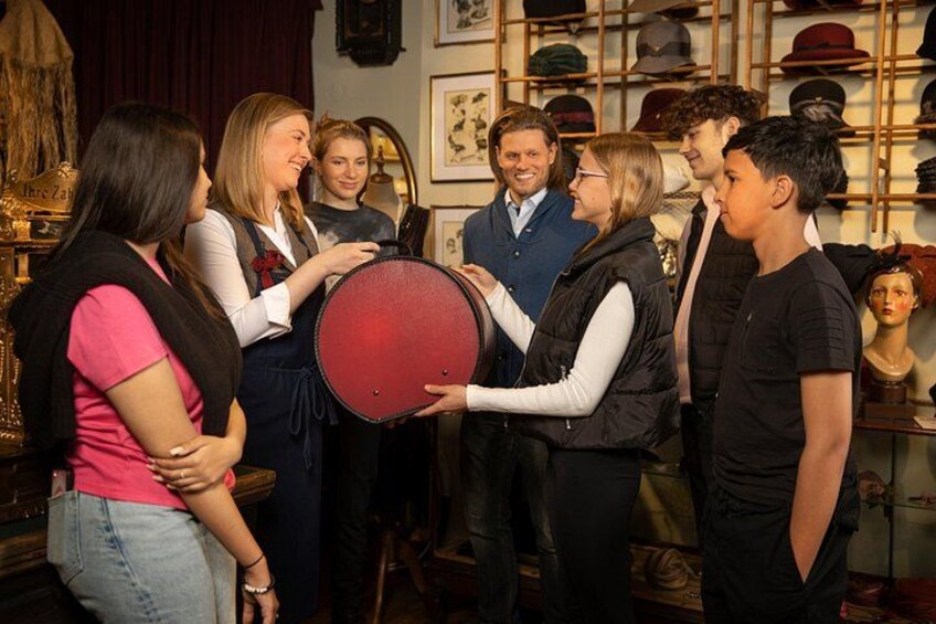 A group of people in a hat shop, some holding hats. 3