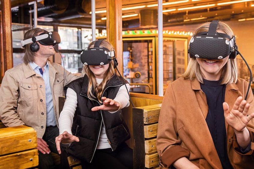 Tres personas usando cascos de realidad virtual sentadas en bancos de madera en una cafetería. 1