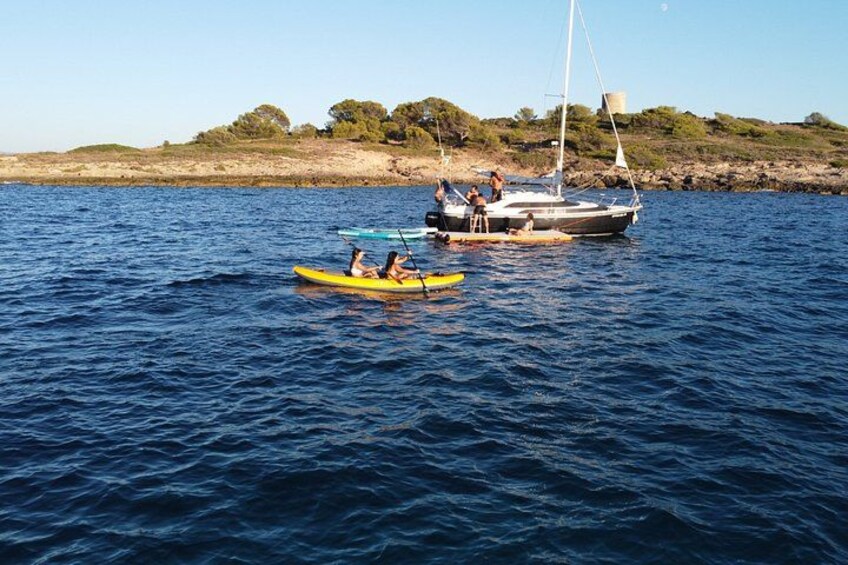 Un mar tranquilo con un kayak amarillo y un velero. 2
