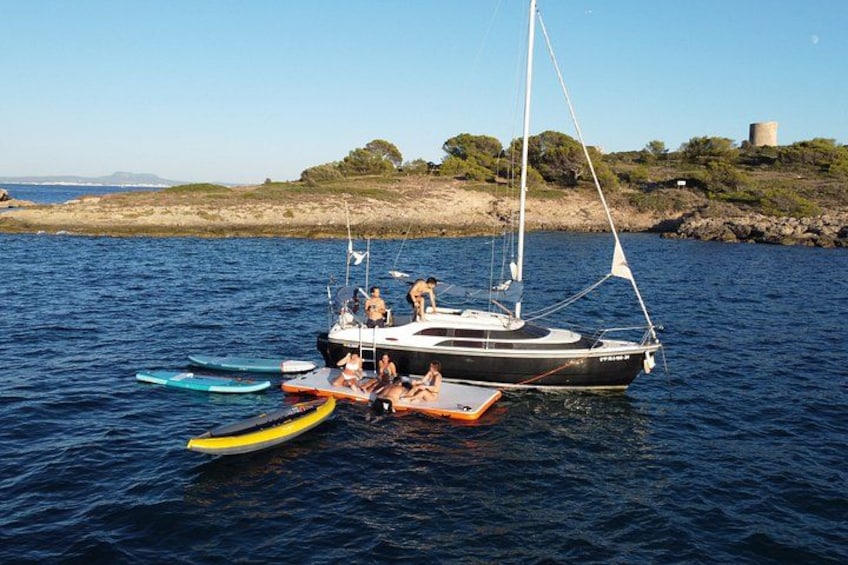 Un velero con gente a bordo y varios botes pequeños en el agua. 5