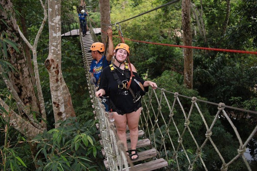 A person on a rope bridge in a forested area. 2