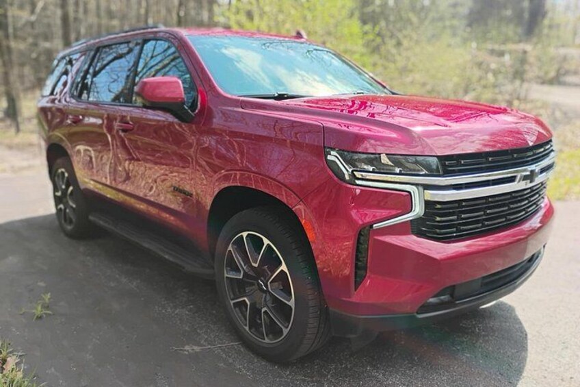 En röd SUV står parkerad på en asfalterad yta med en skog i bakgrunden. 4