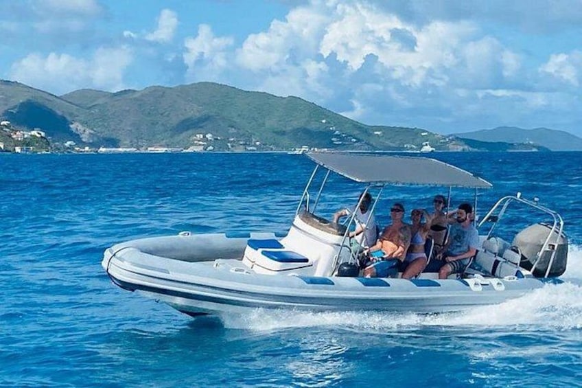 Un motoscafo con quattro persone sull'acqua, cielo sereno e colline in lontananza. 1