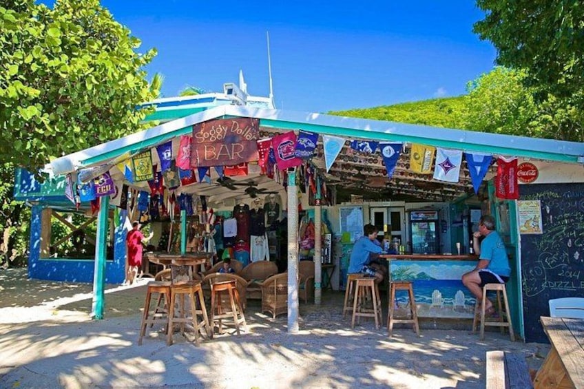 A beachside bar with wooden stools and a blue awning. 2