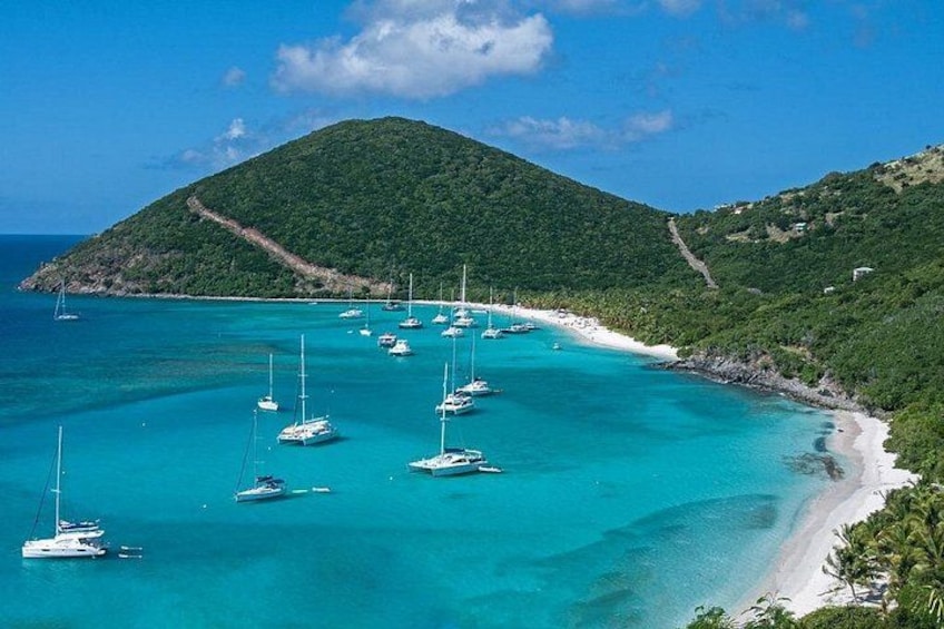 A turquoise sea with sailboats, a white sandy beach, and a green hill. 4