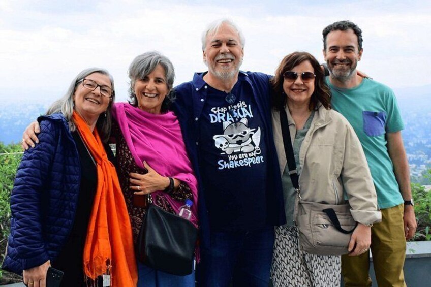 Un grupo de personas de pie en una colina, con una vista panorámica de montañas al fondo. 5