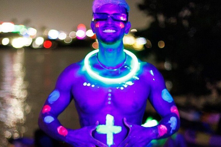 A person with glowing blue and purple body paint and a white cross symbol. 3