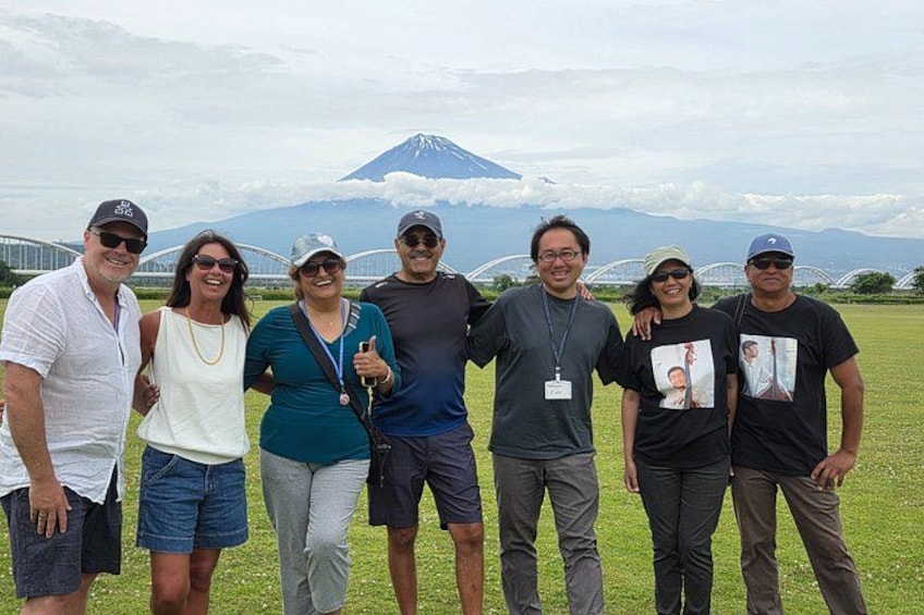A group of people standing in a grassy field with a mountain in the background. 1