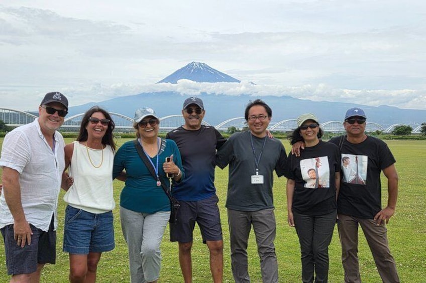 A group of people standing in a grassy field with a mountain in the background. 1
