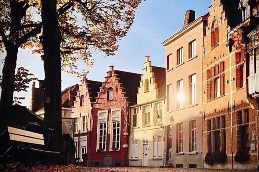 A row of historic buildings with distinct architectural styles, including a red building with a gabled roof and a beige building with a flat facade. 1