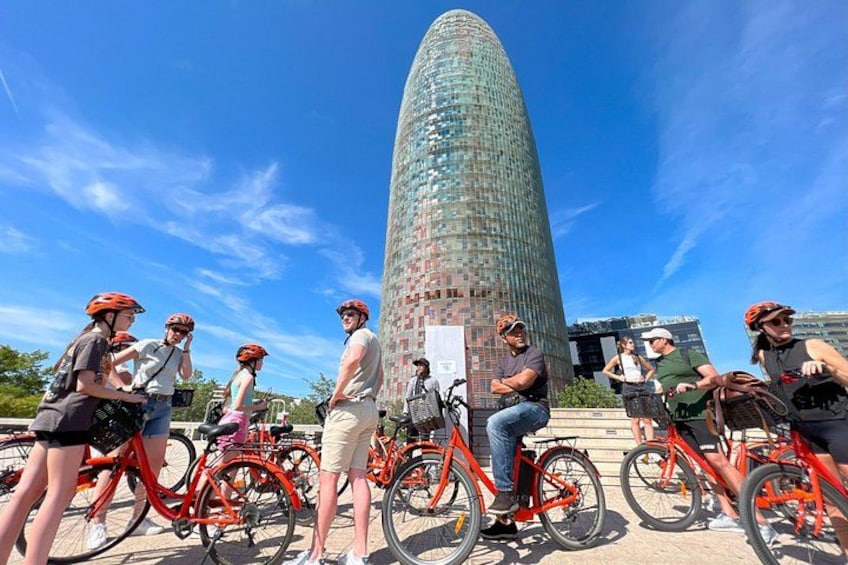A group of people on bicycles in front of a tall, modern glass building. 1