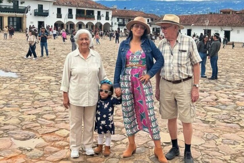 Una piazza lastricata con edifici storici, una folla e una famiglia che posa per una foto. 1