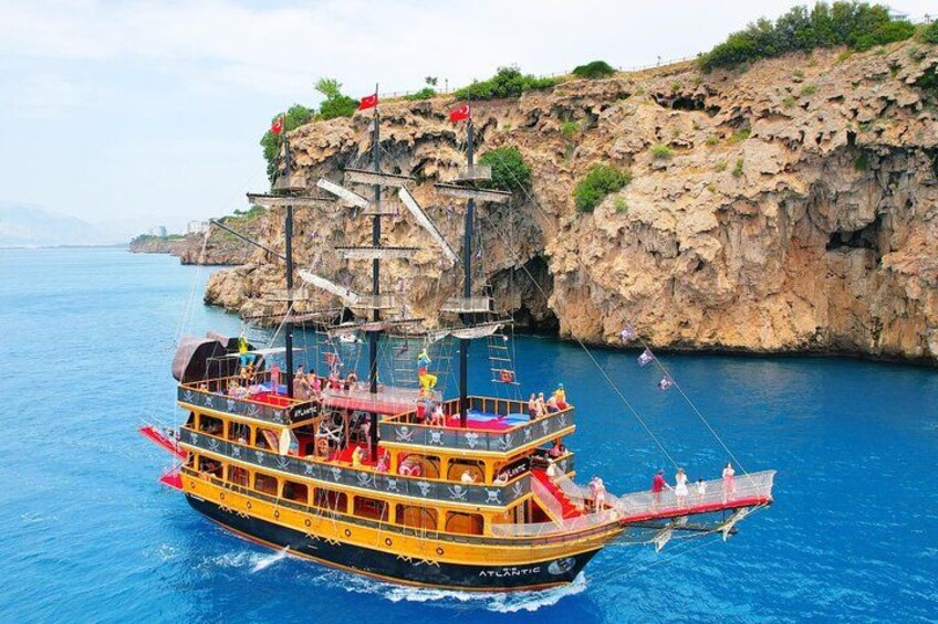 Ein mit Passagieren besetztes, zweistöckiges Boot namens 'ATLANTIS' fährt an steilen Felsen entlang. 3