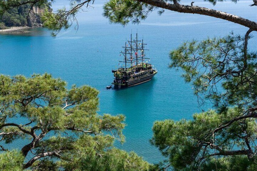 Un barco de gran tamaño anclado en una bahía azul cristalina rodeada de pinos. 2