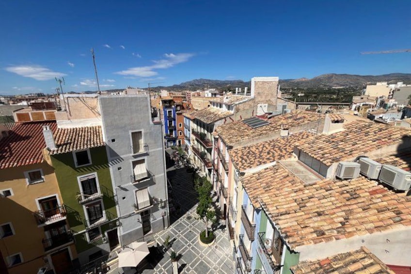 Un paysage urbain mêlant bâtiments modernes et traditionnels, un ciel bleu dégagé et des collines à l’horizon. 2